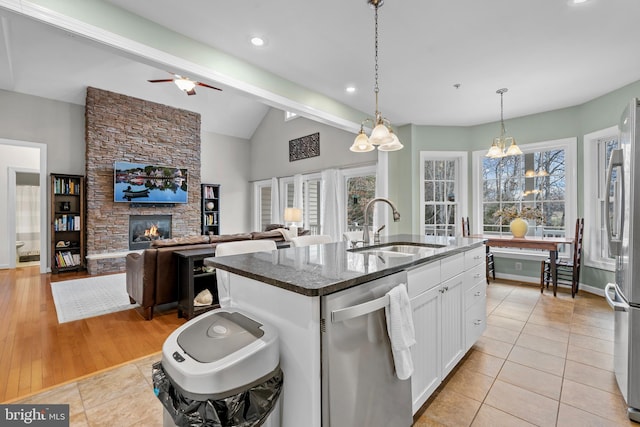 kitchen with lofted ceiling with beams, light tile patterned flooring, a sink, stainless steel appliances, and white cabinets