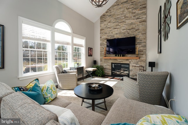 living area with a stone fireplace and high vaulted ceiling