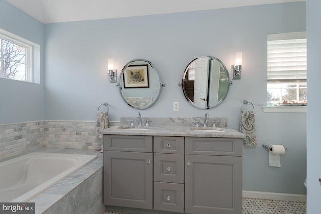 bathroom featuring a healthy amount of sunlight, a garden tub, and a sink