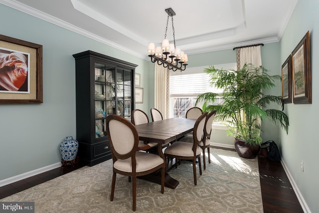 dining area featuring a tray ceiling, wood finished floors, and baseboards