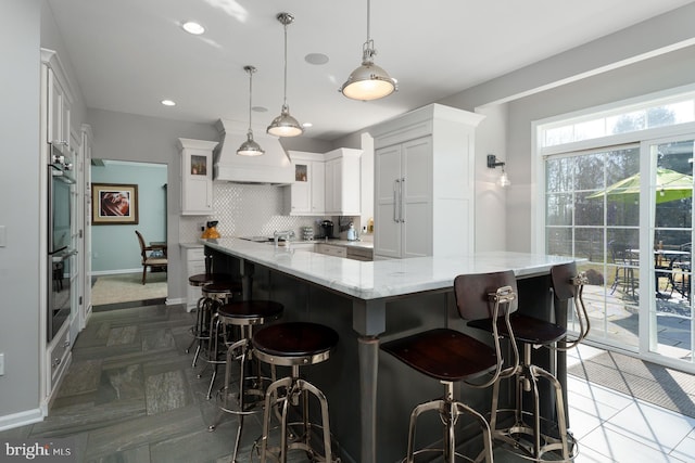 kitchen with a breakfast bar, backsplash, stainless steel double oven, white cabinets, and glass insert cabinets