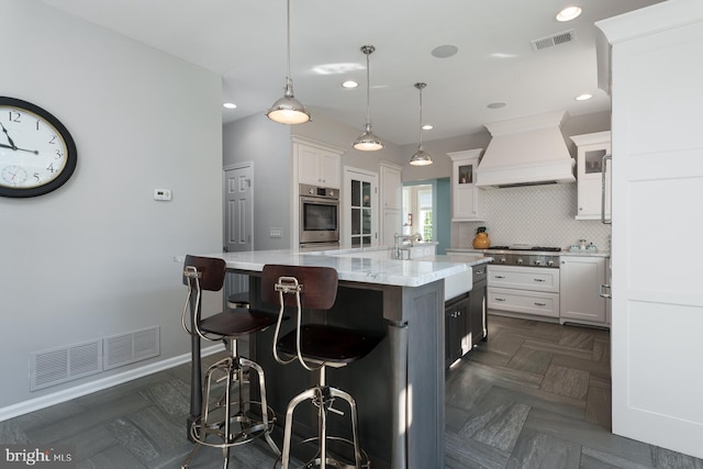 kitchen featuring custom exhaust hood, visible vents, backsplash, and appliances with stainless steel finishes