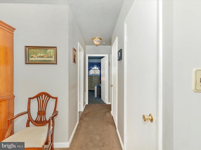 hallway featuring light carpet and baseboards