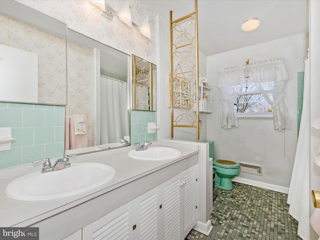 full bathroom with wallpapered walls, double vanity, toilet, and a sink