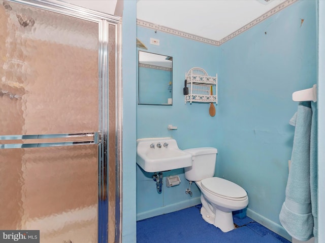 bathroom with a sink, baseboards, toilet, and a shower stall