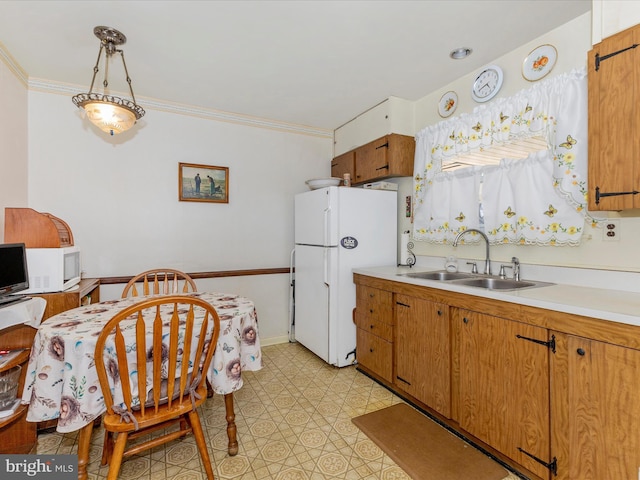 kitchen featuring crown molding, white appliances, light countertops, and a sink