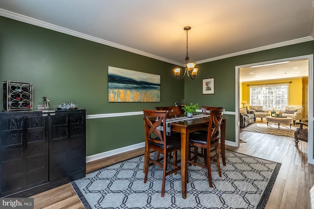 dining room featuring baseboards, a notable chandelier, wood finished floors, and crown molding