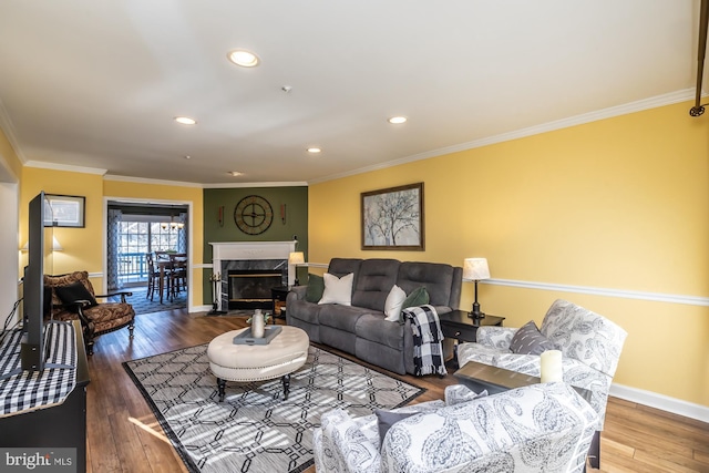 living room featuring recessed lighting, wood-type flooring, crown molding, a premium fireplace, and baseboards