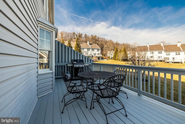 deck with a residential view, a grill, and outdoor dining space