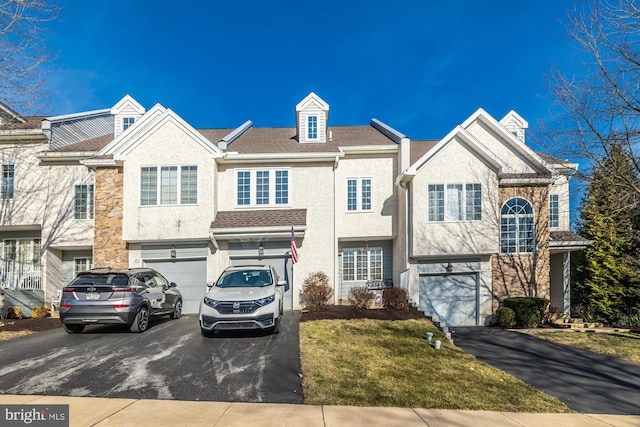 multi unit property featuring an attached garage, stone siding, and driveway