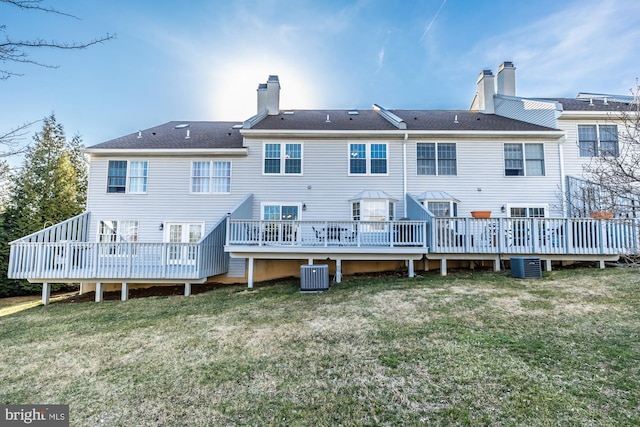 rear view of house with a wooden deck, cooling unit, a yard, and a chimney