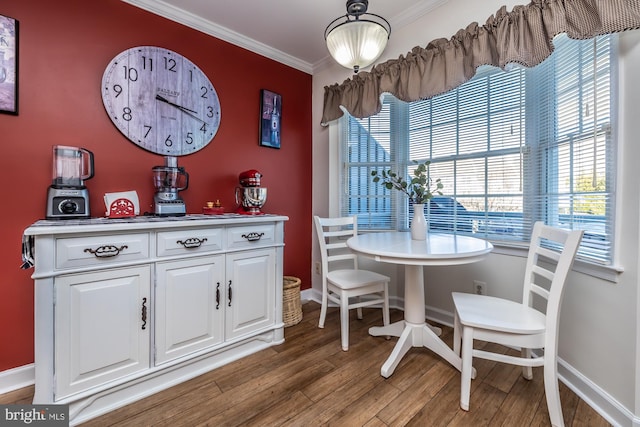 dining space featuring crown molding, wood finished floors, and baseboards