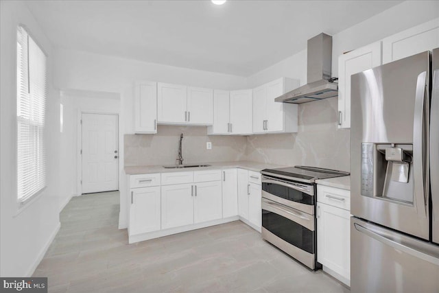 kitchen featuring a sink, wall chimney range hood, tasteful backsplash, stainless steel appliances, and light countertops