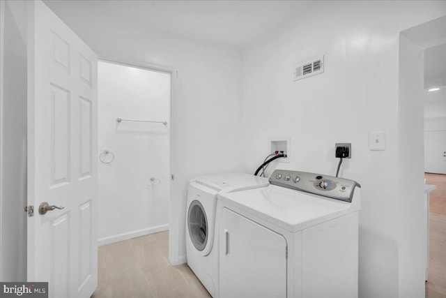 washroom with washing machine and clothes dryer, visible vents, baseboards, light wood-type flooring, and laundry area