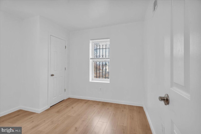 spare room with light wood-type flooring, baseboards, and visible vents