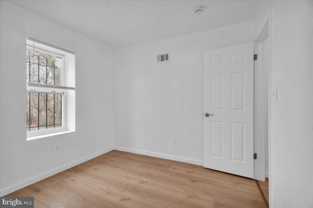 unfurnished room with light wood finished floors, visible vents, and baseboards