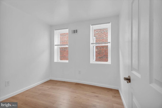 unfurnished room featuring visible vents, light wood-style floors, and baseboards