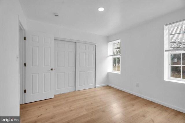 unfurnished bedroom featuring recessed lighting, light wood-style floors, baseboards, and a closet