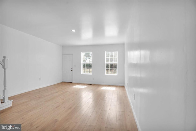 unfurnished living room with light wood-type flooring and baseboards