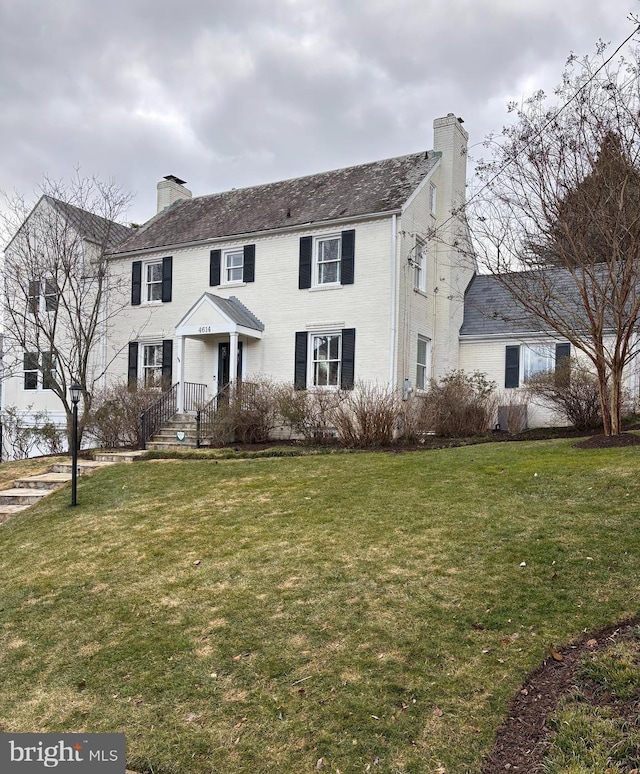 colonial house featuring a chimney and a front lawn