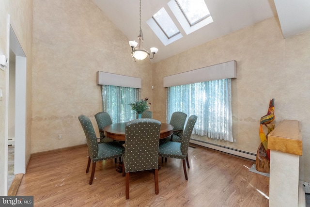 dining area featuring wood finished floors, high vaulted ceiling, a baseboard radiator, a skylight, and a chandelier