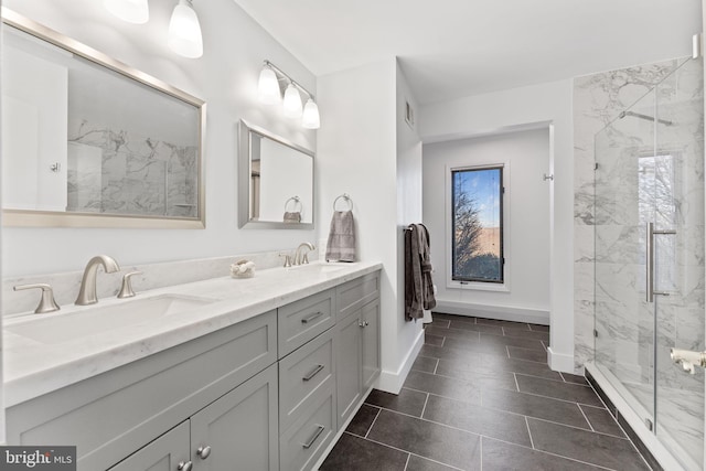 bathroom with a marble finish shower, double vanity, and a sink