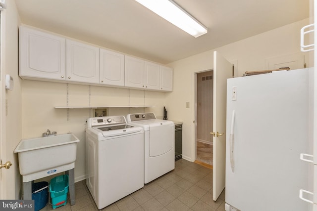 clothes washing area with a sink, cabinet space, and washer and clothes dryer