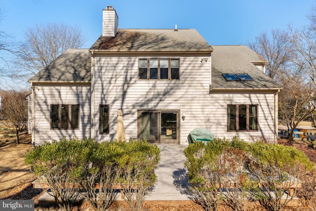 view of front facade with a shingled roof and a chimney