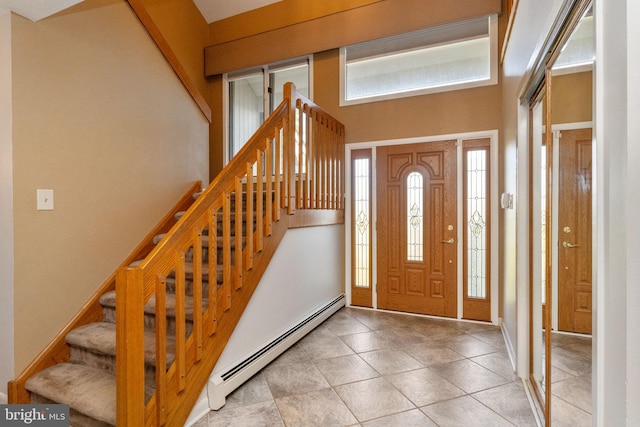 tiled entrance foyer with stairway, a healthy amount of sunlight, and a baseboard heating unit