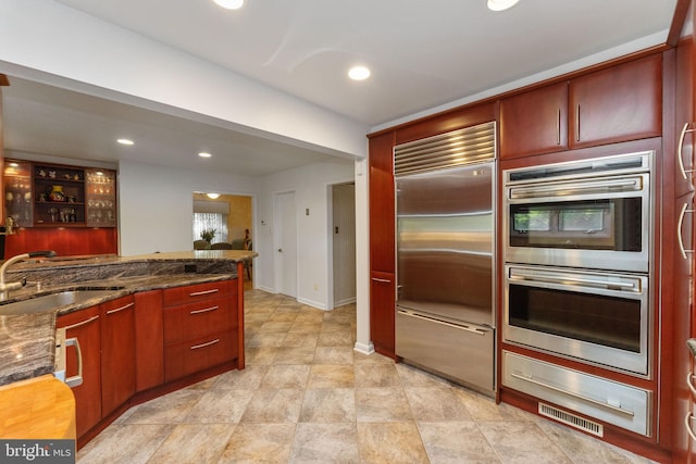 kitchen with visible vents, dark stone counters, recessed lighting, stainless steel appliances, and a sink