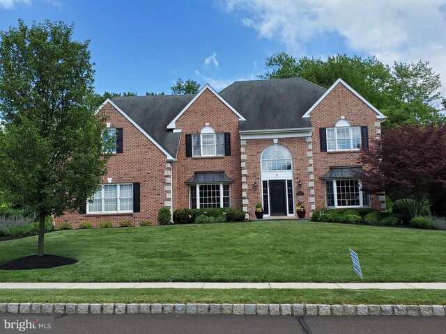 view of front of house featuring a front yard, brick siding, and roof with shingles