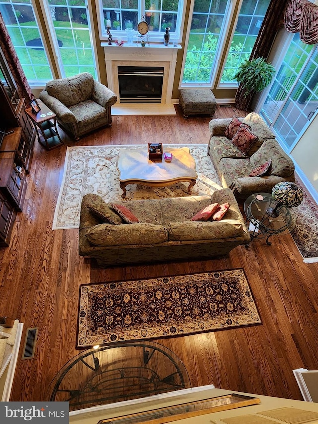 living area featuring a glass covered fireplace, wood finished floors, and visible vents