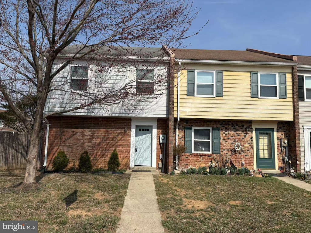 townhome / multi-family property with a front yard and brick siding