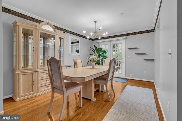 dining area featuring an inviting chandelier, crown molding, light wood-style floors, and baseboards