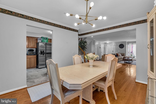 dining room featuring a chandelier, light wood-style flooring, baseboards, and ornamental molding