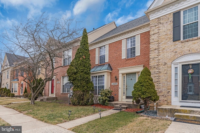 multi unit property with a front yard and brick siding