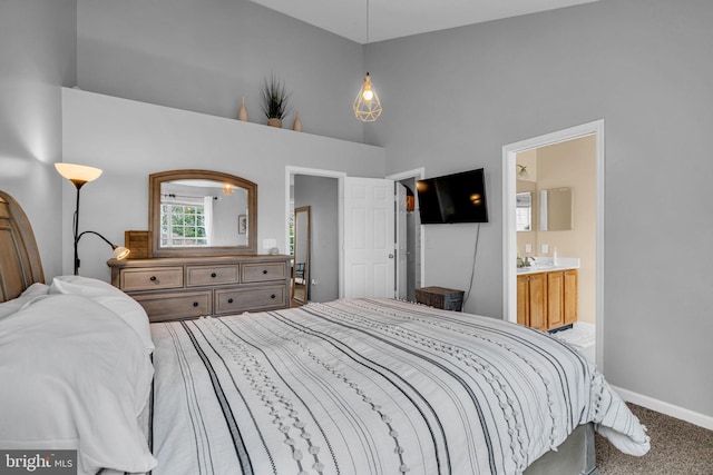 carpeted bedroom featuring baseboards, high vaulted ceiling, and ensuite bath