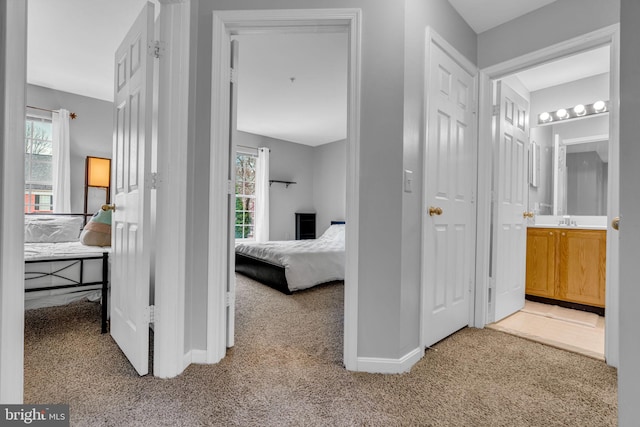 hallway with a sink, baseboards, and carpet flooring