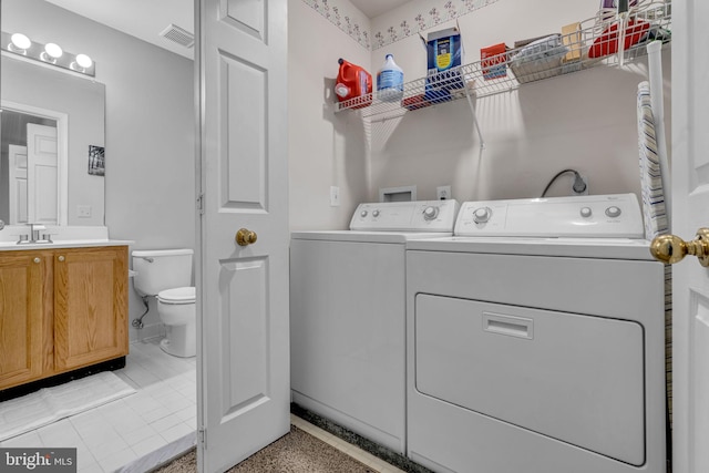 laundry room featuring washing machine and clothes dryer, visible vents, laundry area, and a sink