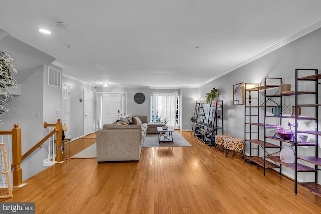 living room with visible vents, baseboards, wood finished floors, and ornamental molding