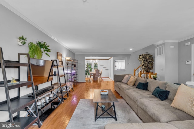 living area featuring stairs, crown molding, a notable chandelier, and wood finished floors