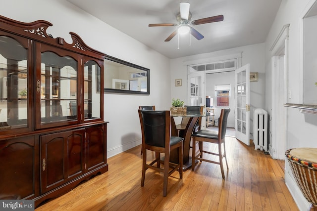 dining space featuring light wood-style flooring, radiator, a ceiling fan, and baseboards