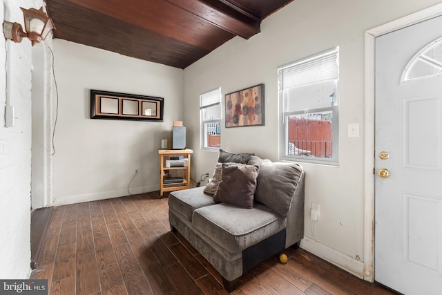 sitting room with dark wood finished floors, beam ceiling, baseboards, and wooden ceiling