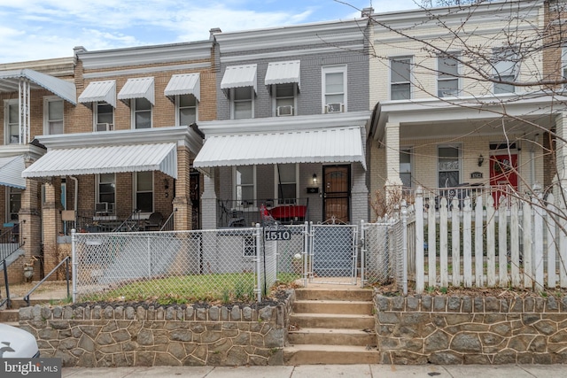 view of property with brick siding, covered porch, and a gate