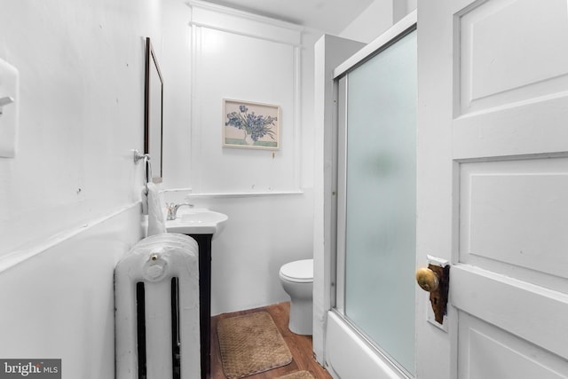 full bathroom featuring a sink, radiator, toilet, and wood finished floors