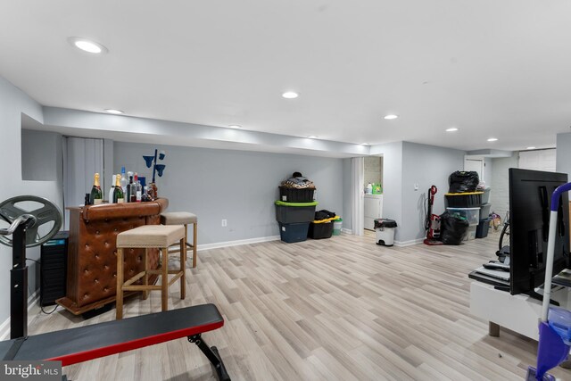 exercise room with recessed lighting, light wood-type flooring, baseboards, and washer / clothes dryer