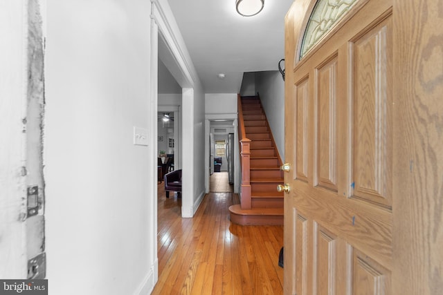 entrance foyer with light wood-type flooring, stairway, and baseboards