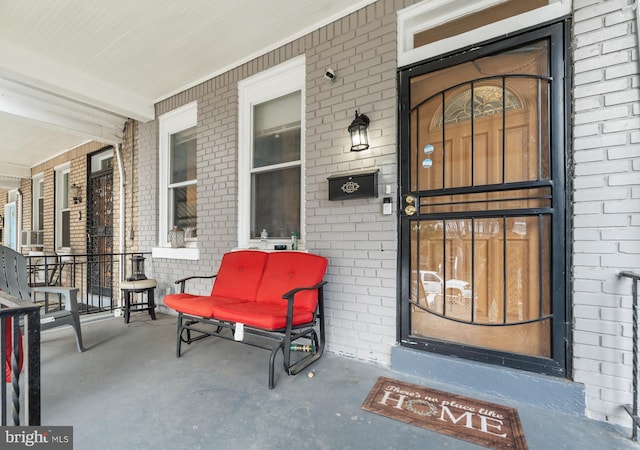 doorway to property featuring brick siding and a porch