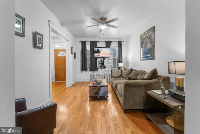 living room featuring ceiling fan, baseboards, radiator heating unit, and light wood-style floors