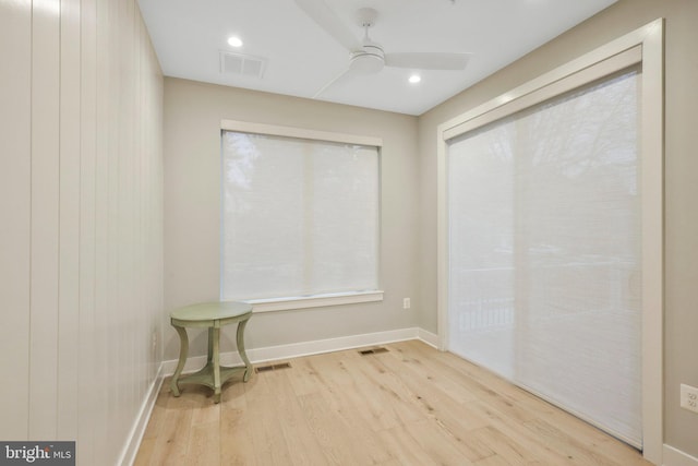 empty room featuring ceiling fan, visible vents, baseboards, and wood finished floors